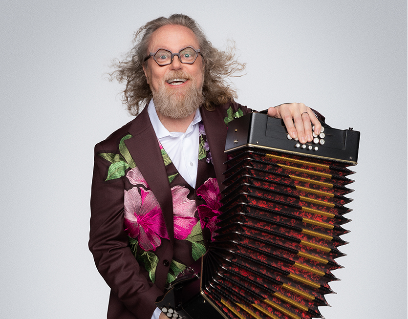 Porträtt av Antti Paalanen med en blommig kavaj och ett dragspel